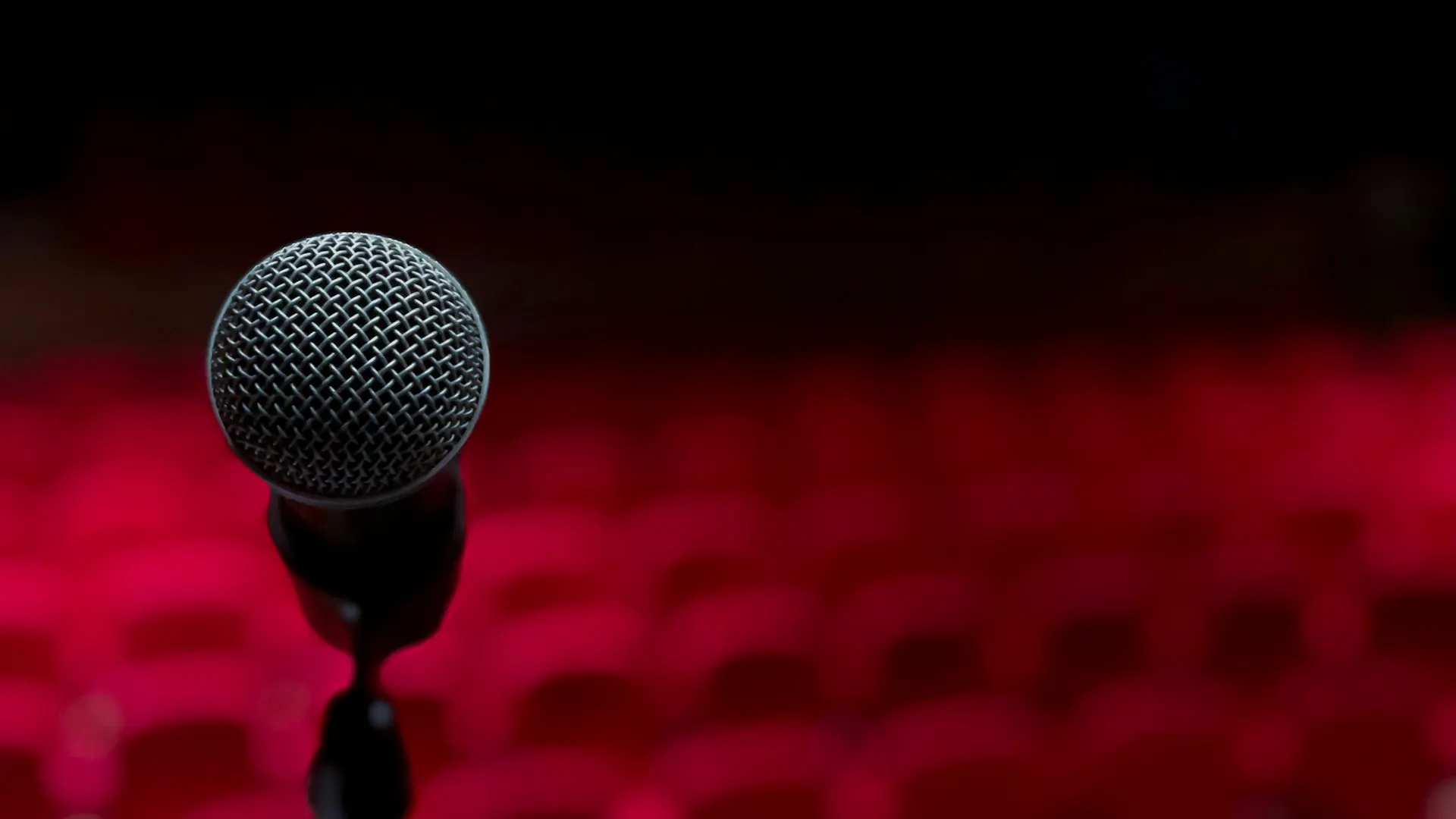 Un micro de scène devant les fauteuils rouges d'une salle de spectacle